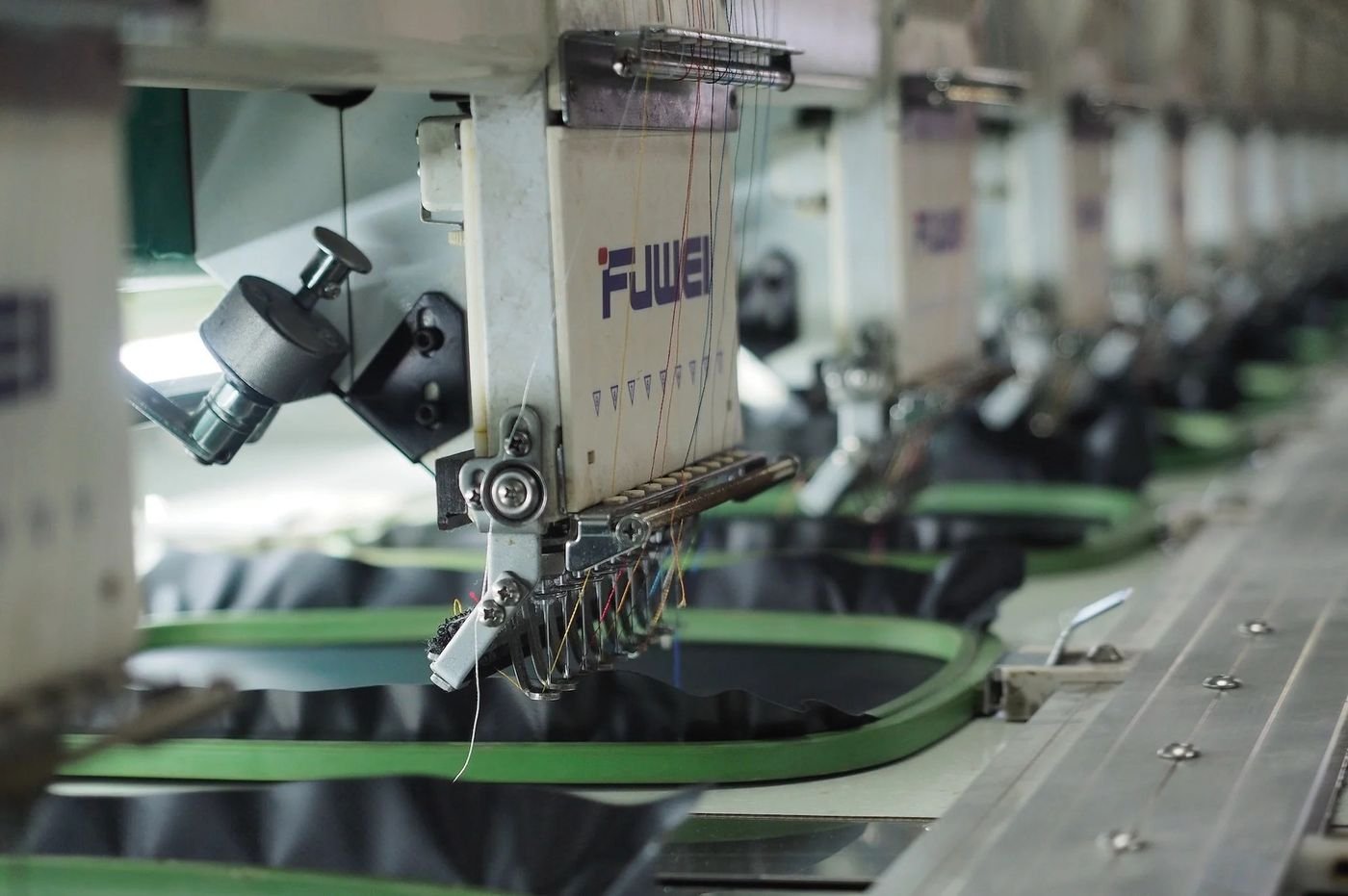 Industrial embroidery machines stitching garments in a working factory